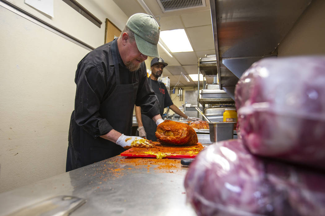 New employee Ron Cochran adds some rub to a large brisket during training from kitchen prep/smo ...