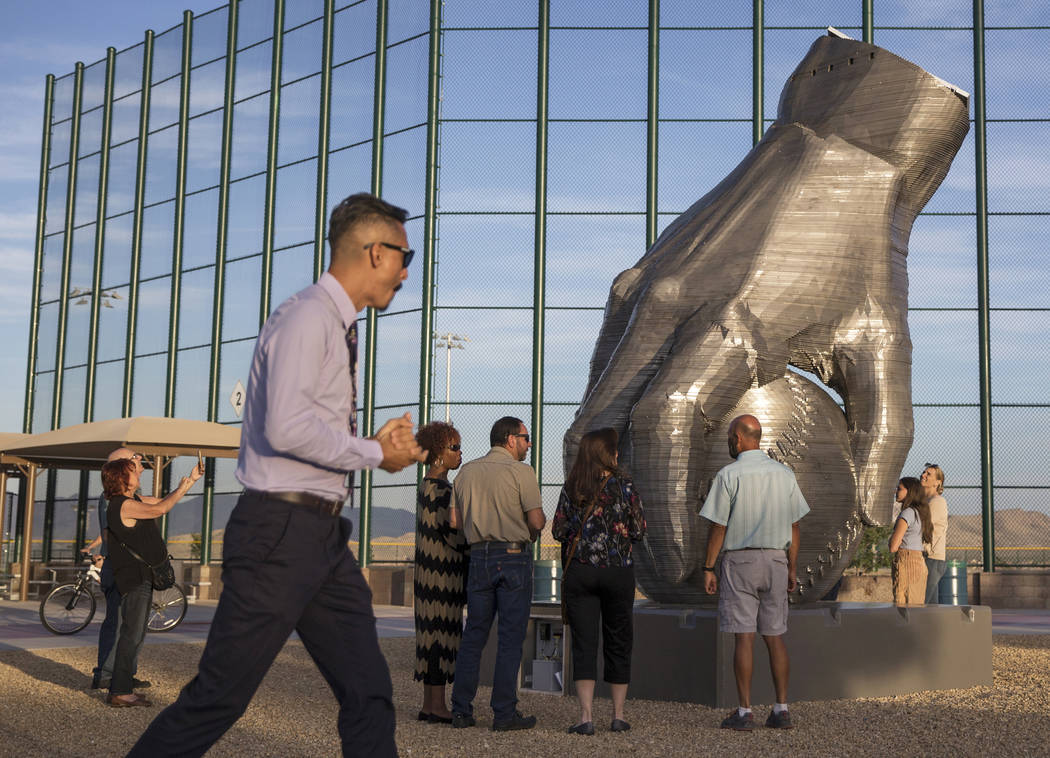 Artist Luis Varela-Rico, left, passes by his sculpture "Organic Study No. 2" during a ...