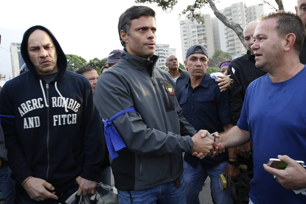 Opposition leader Leopoldo Lopez, center, is greeted by a supporter outside La Carlota air base ...