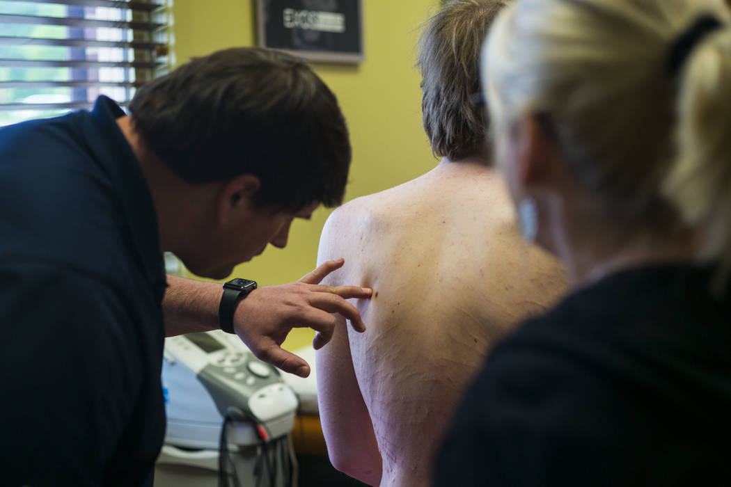 Physical therapist Walker Gardner, left, examines Grayson McClure at EXOS Physical Therapy & Sp ...