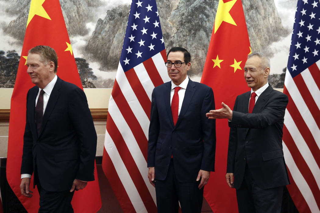 Chinese Vice Premier Liu He, right, shows the way to U.S. Treasury Secretary Steven Mnuchin, ce ...