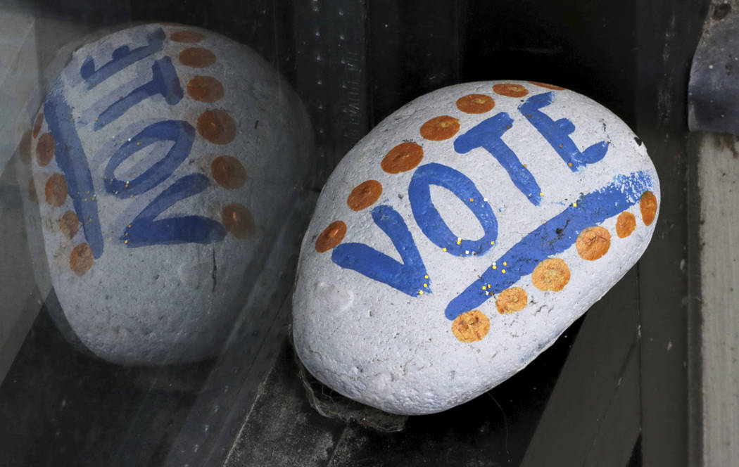 A stone painted with the word "VOTE" rests March 22, 2019, on the window sill of an art gallery ...