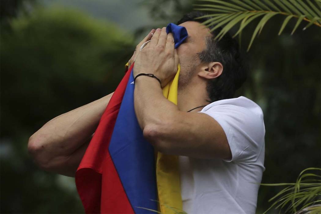 Opposition leader Leopoldo Lopez kisses a Venezuelan national flag as he greets supporters outs ...