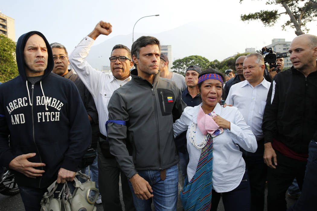 Opposition leader Leopoldo Lopez, center, is seen surrounded by supporters outside La Carlota a ...