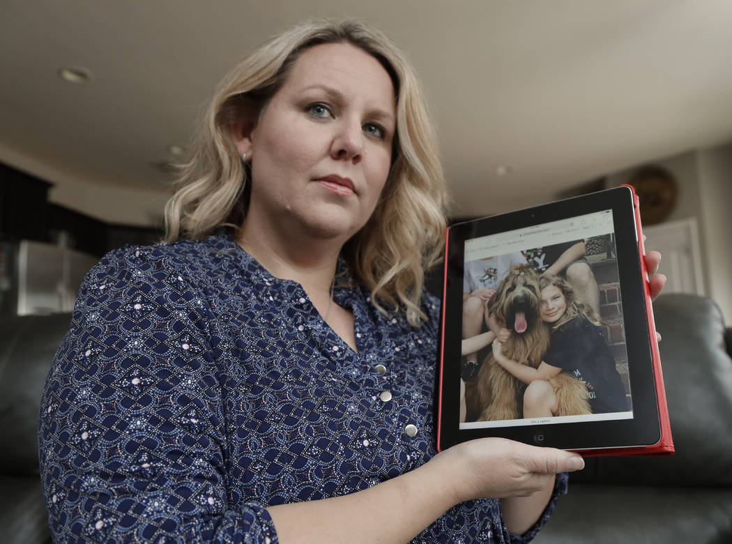 Rachel Cummings holds a photo of her daughter, Sobie, with their former service dog, Okami, at ...