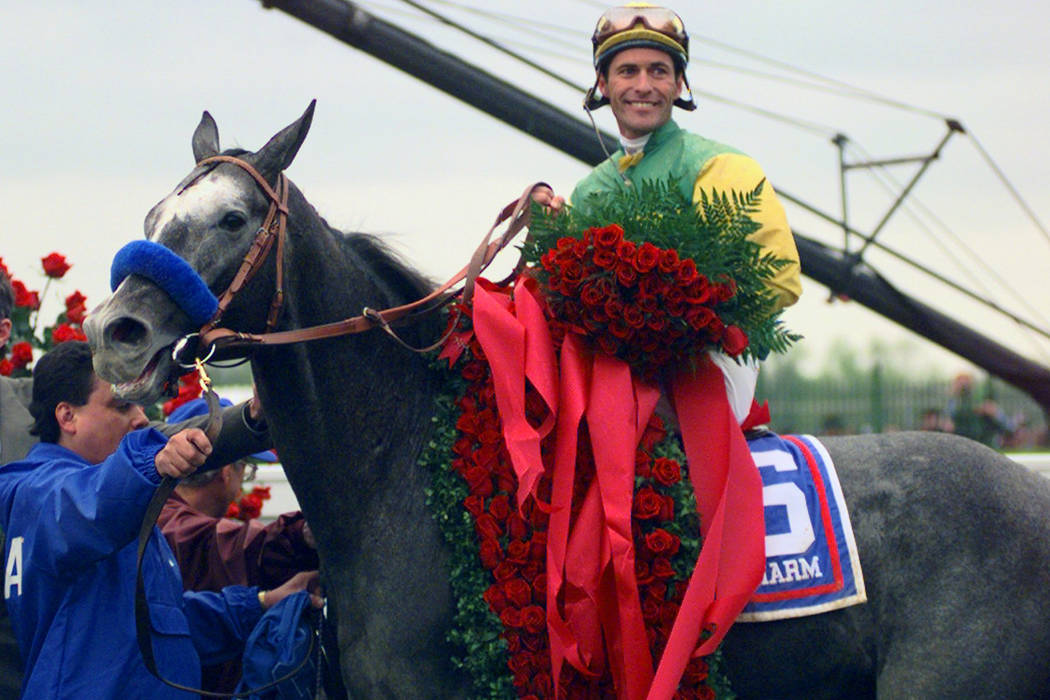 Jockey Gary Stevens and Silver Charm wear the signature roses in the winner's circle after winn ...