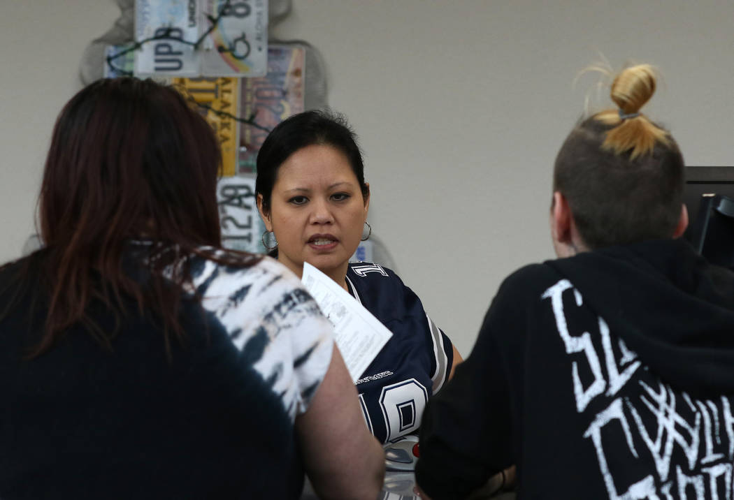 A DMV service technician, who declined to give her name, helps customers at the East Sahara DMV ...