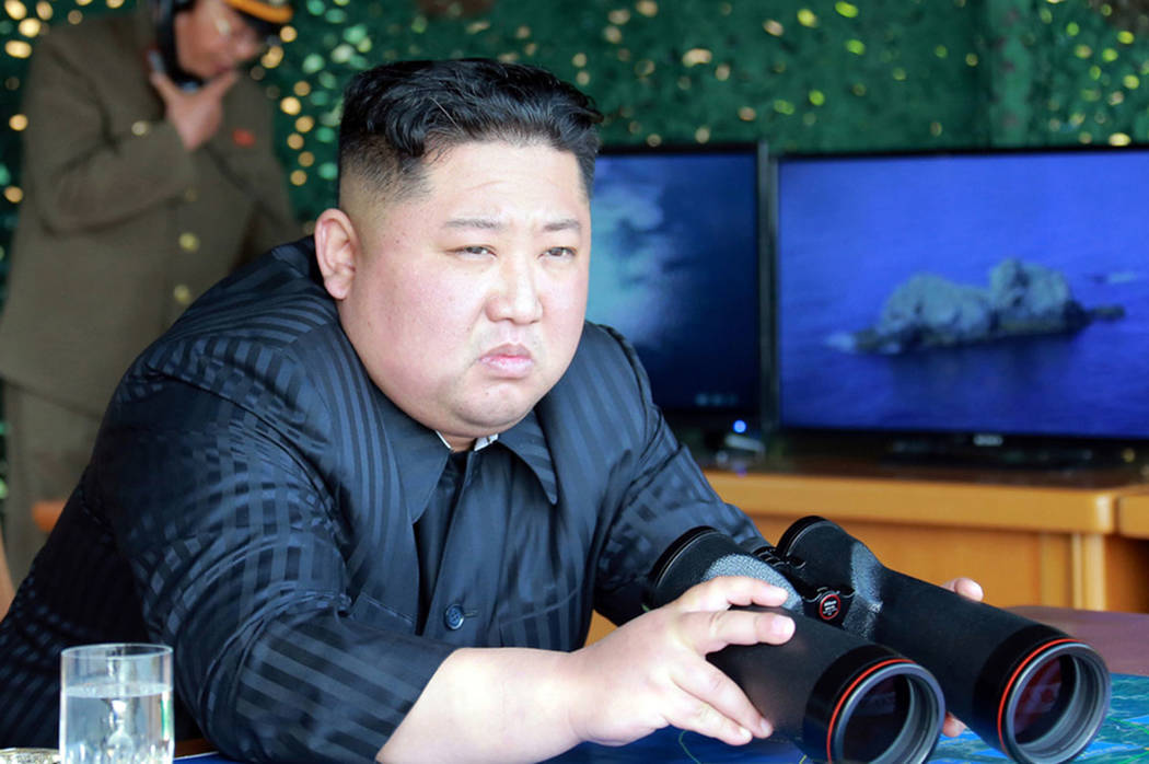 North Korean leader Kim Jong Un, equipped with binoculars, observes tests of different weapons ...