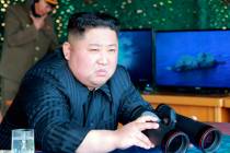 North Korean leader Kim Jong Un, equipped with binoculars, observes tests of different weapons ...