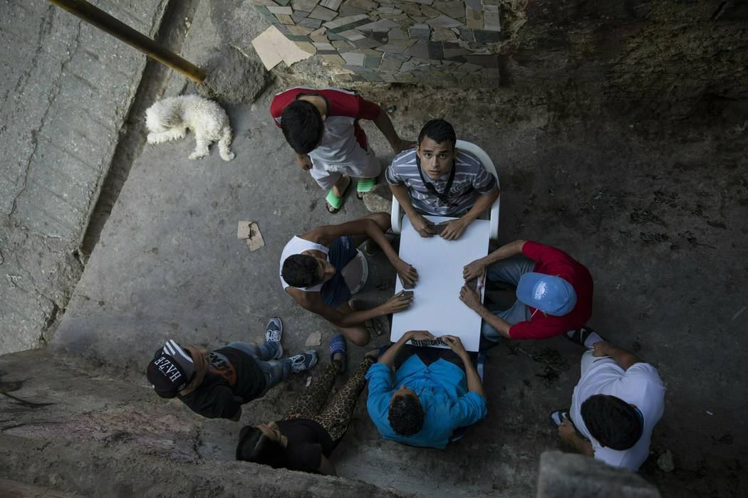 Men play dominoes in the Petare shanty town, in Caracas, Venezuela, Friday, May 3, 2019. (AP Ph ...