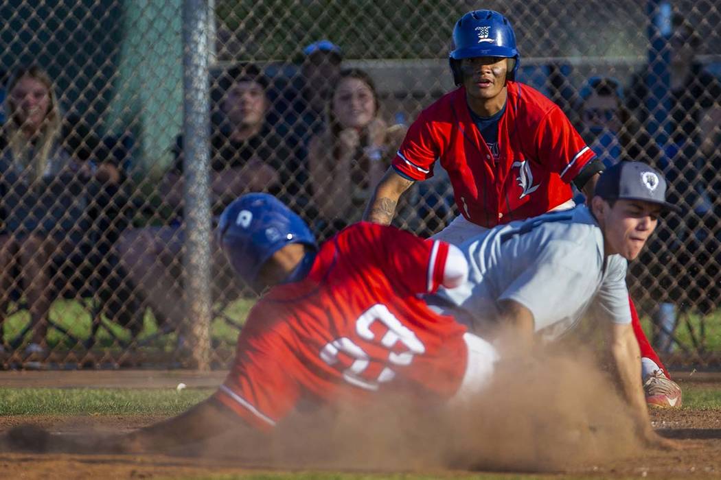 Liberty's Mason Bowden (1) looks on as teammate Ky Yamamoto (23) slides safely into home plate ...