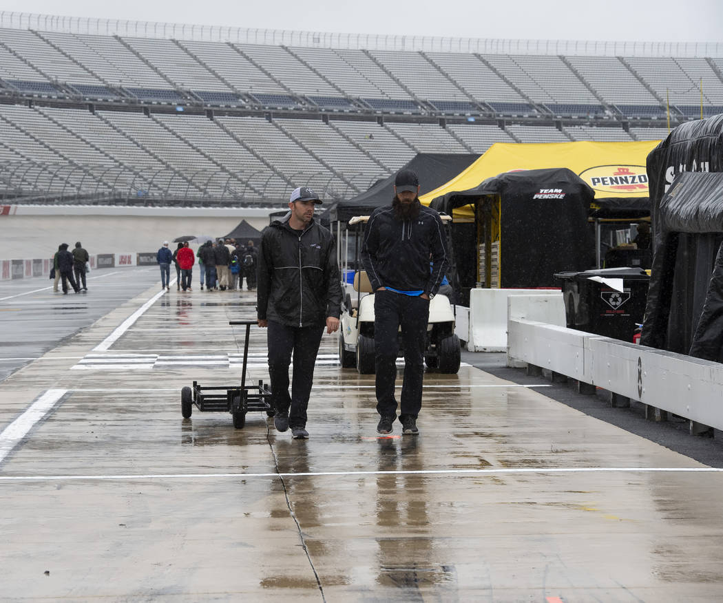 People walk in the pits area as rain falls before a NASCAR Cup series auto race at Dover Intern ...