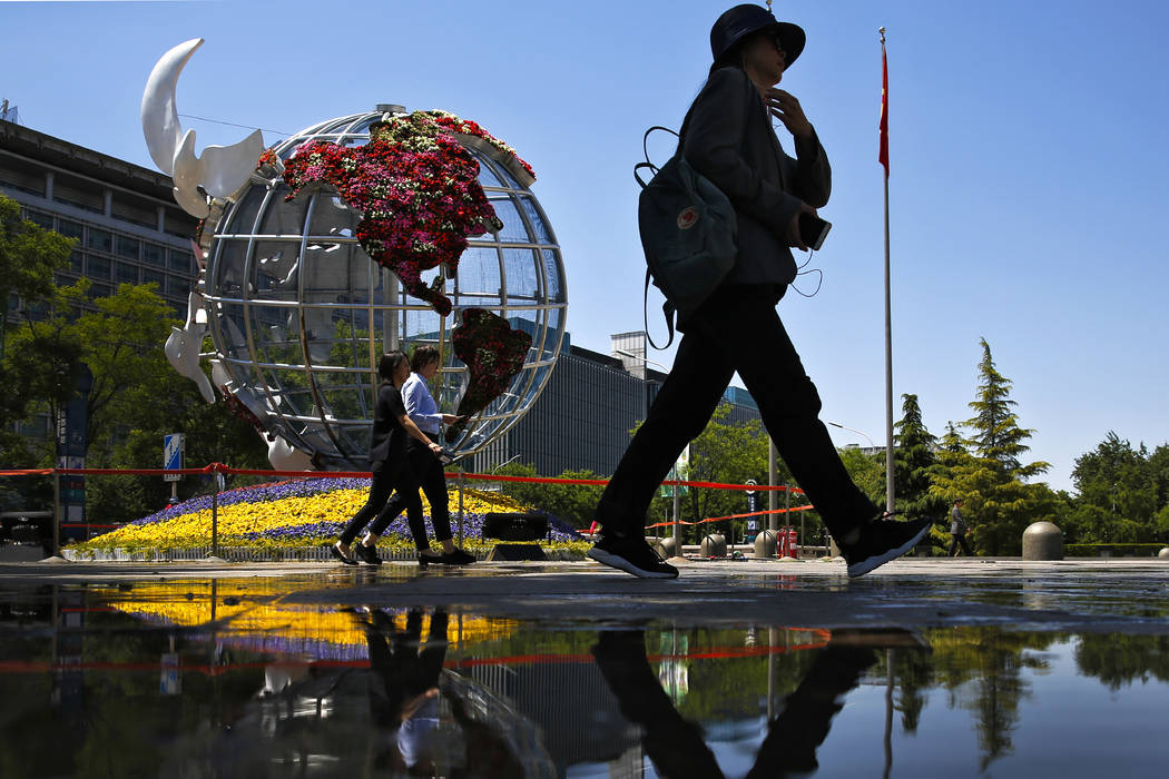 People walk by a globe structure showing the United States of America on display outside a bank ...