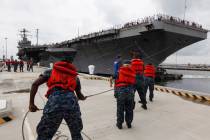 Navy shore crew haul in lines as the nuclear-powered aircraft carrier USS Abraham Lincoln arriv ...