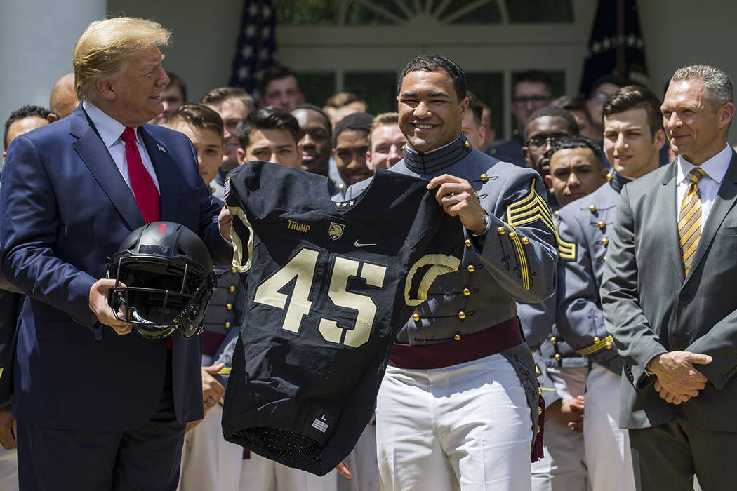 President Donald Trump accepts a jersey from Army running back Darnell Woolfolke Army during th ...