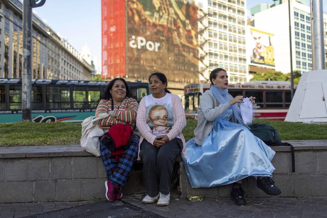 A woman dressed as Eva Peron sits next to other two women, in Buenos Aires, Argentina, Monday, ...