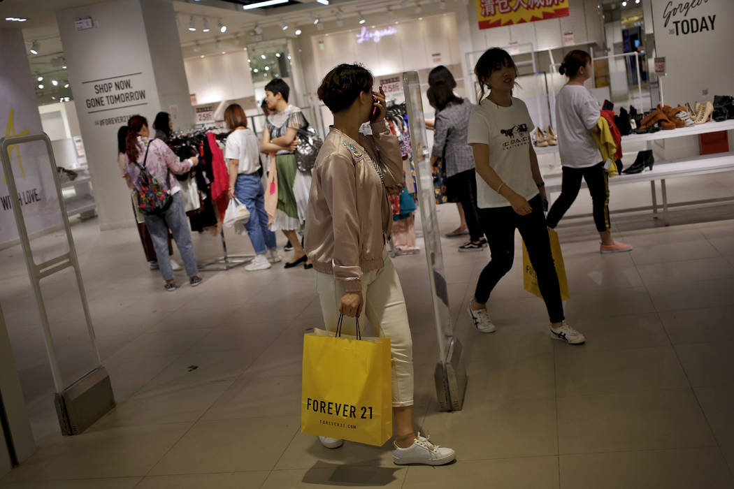 Chinese women carry paper bag of Forever 21, an American fast fashion retailer which is offerin ...