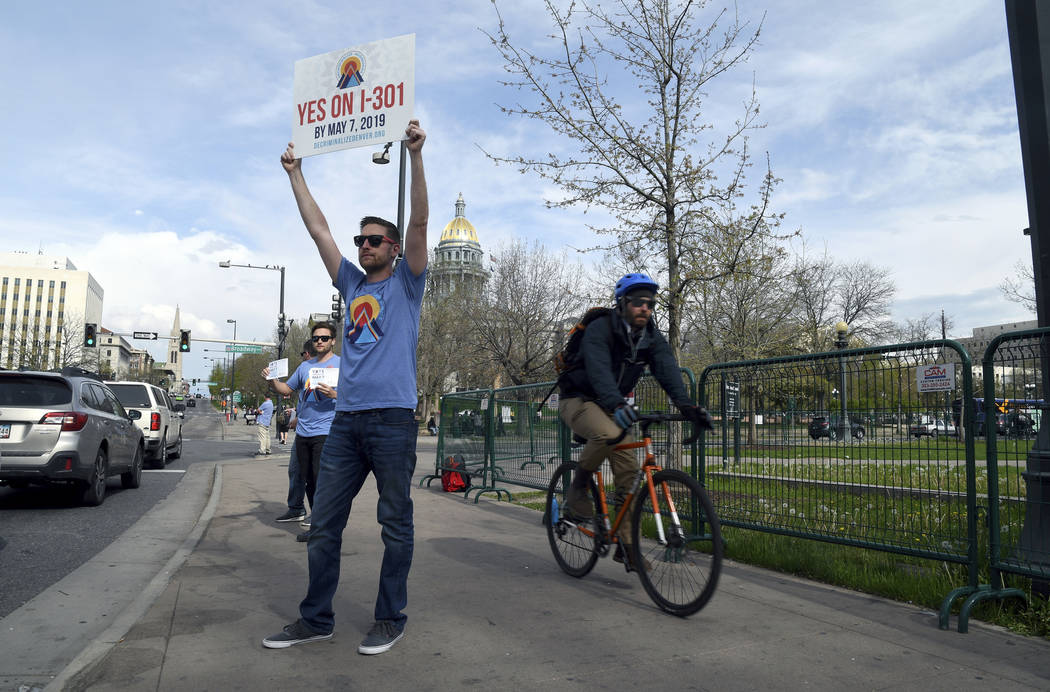 Chris Olson holds a sign near a busy intersection in downtown Denver on Monday, May 6, 2019, ur ...