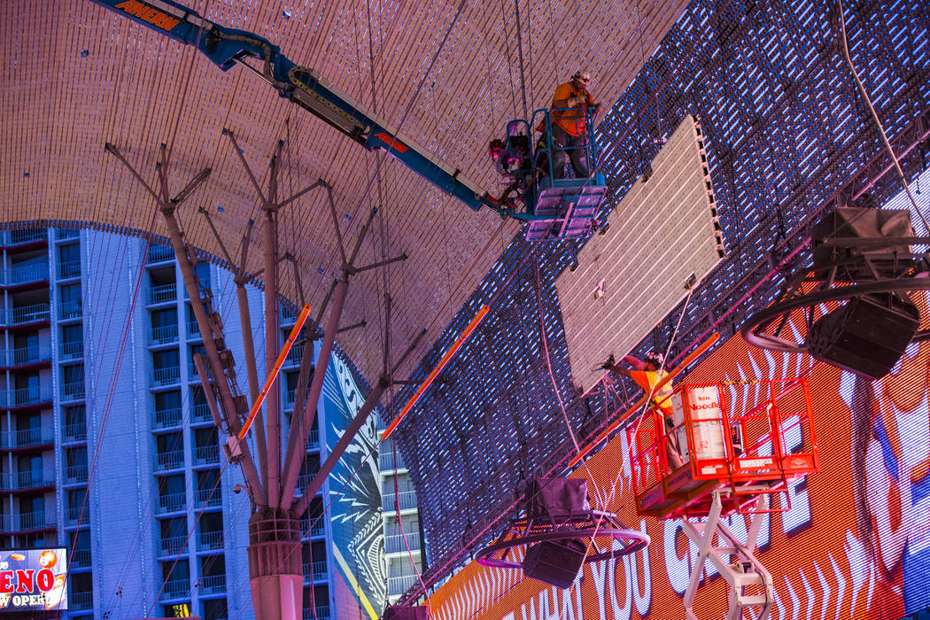 Construction workers lower an old panel during the second day of renovations of the Viva Vision ...