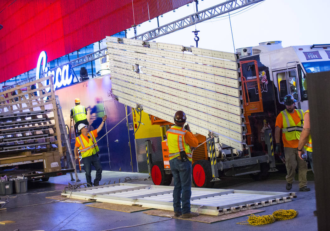 Construction workers lower an old panel during the second day of renovations of the Viva Vision ...