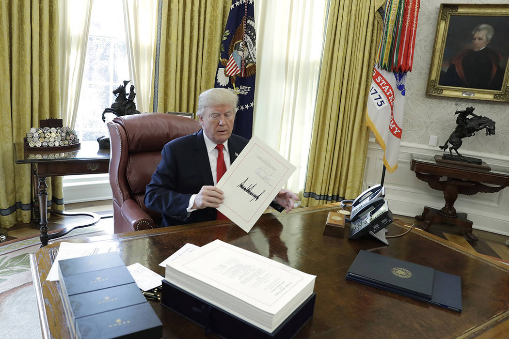 President Donald Trump displays the $1.5 trillion tax overhaul package he had just signed, Frid ...