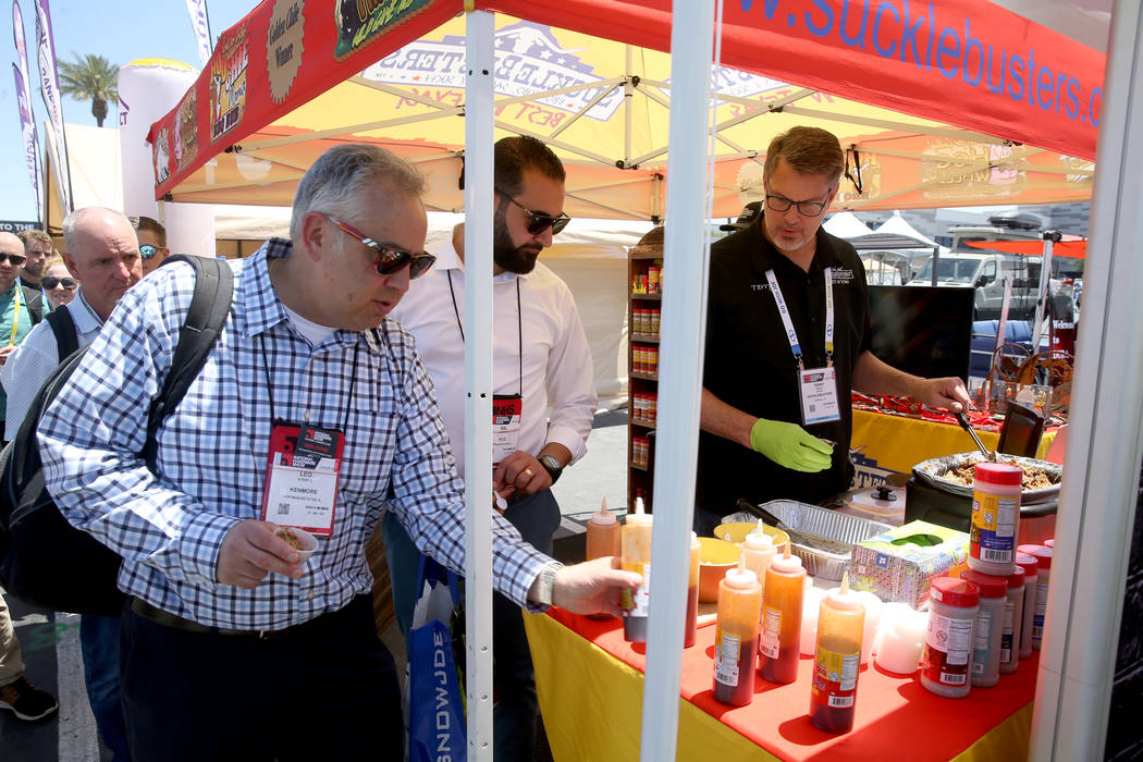 Terry Arnold, of Coppell, Texas, with Sucklebusters, right, gives free samples of his barbecue ...