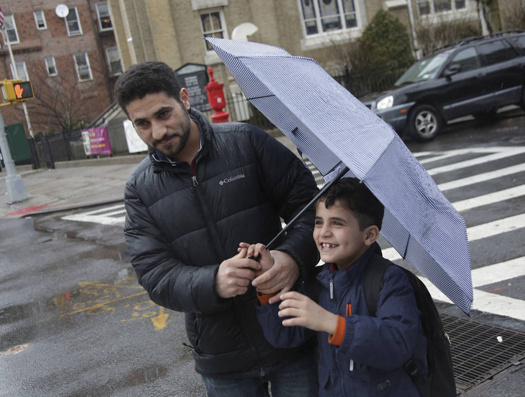 In this Thursday, March 21, 2019, photo, Sadek Ahmed walks with his son Mutaz, 7, after picking ...