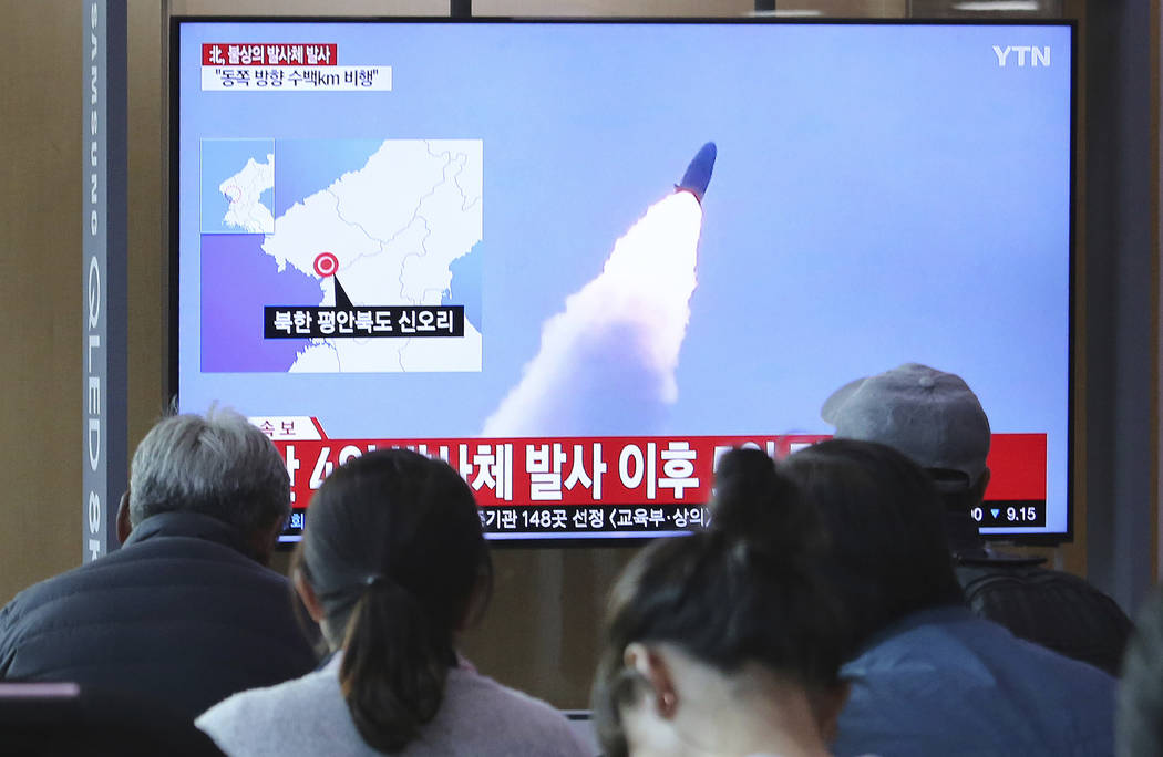 People watch a TV showing file footage of North Korea's missile launch during a news program at ...