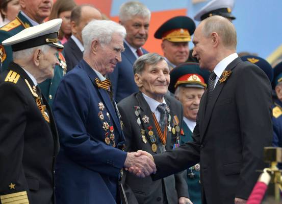 Russian President Vladimir Putin shakes hands with WWII veterans prior to a military parade mar ...