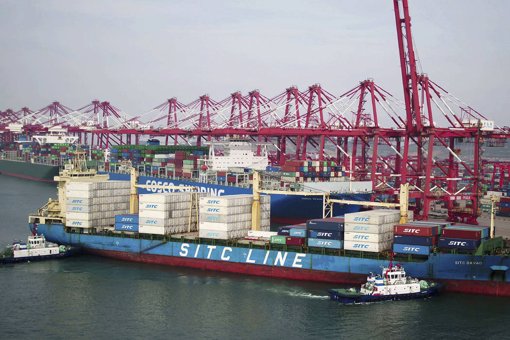 Two barges push a container ship to the dockyard in Qingdao in eastern China's Shandong provinc ...