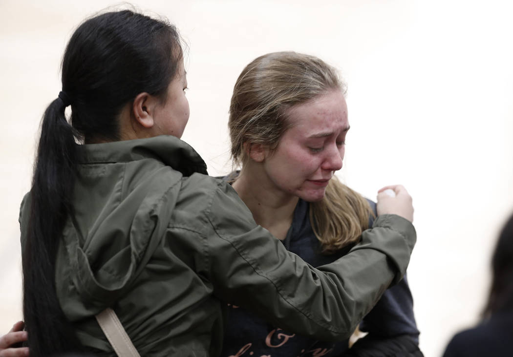 Young women console each other during a community vigil to honor the victims and survivors of y ...