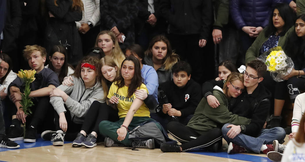 Young people console each other during a community vigil to honor the victims and survivors of ...