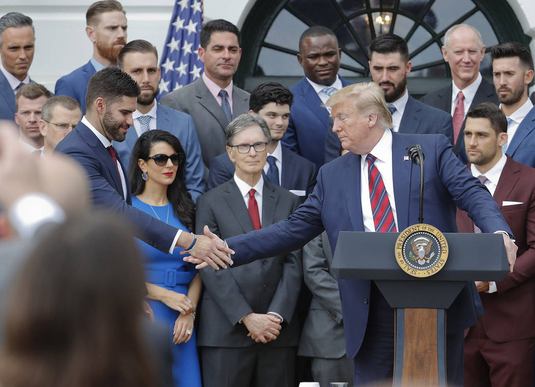 President Donald Trump, right, reaches over to shake hands with outfielder J.D. Martinez, left, ...