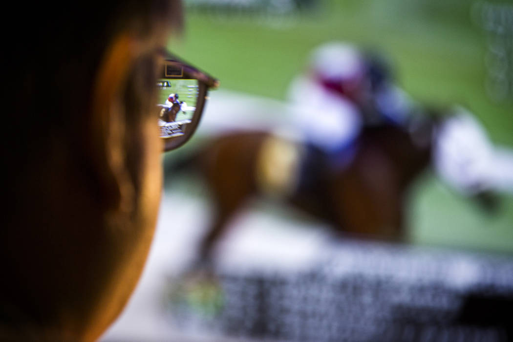 A man watches a horse race on a tv monitor in the William Hill Race & Sports Book at the Plaza ...