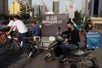 In this Wednesday, May 8, 2019, photo, a delivery man bearing U.S. commerce giant Amazon's bran ...