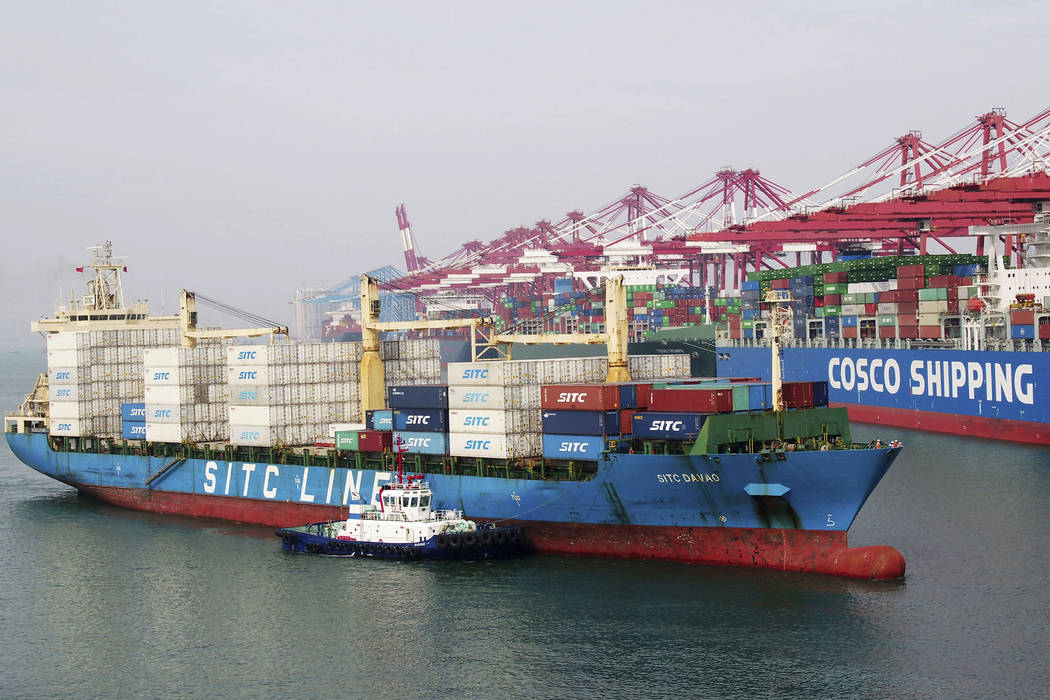 In this Wednesday, May 8, 2019, photo, a barge pushes a container ship to the dockyard in Qingd ...