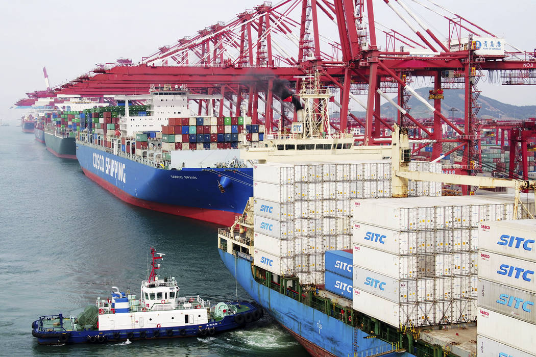 In this Wednesday, May 8, 2019, photo, a barge pushes a container ship to the dockyard in Qingd ...