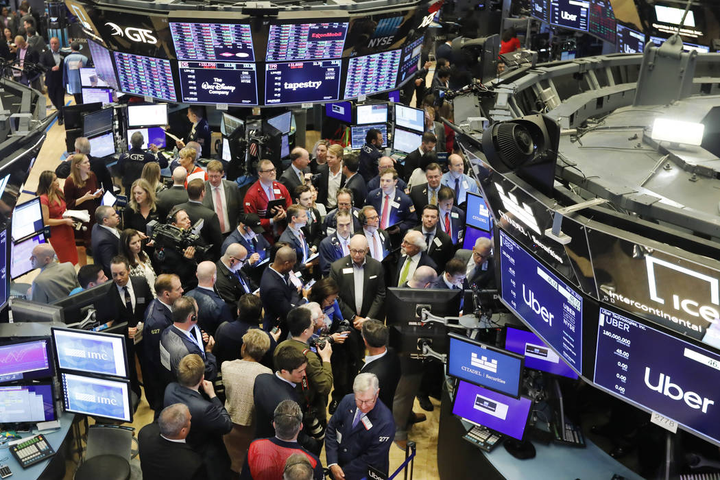 Stock traders gather around the post where Uber shares will begin trading during the company's ...