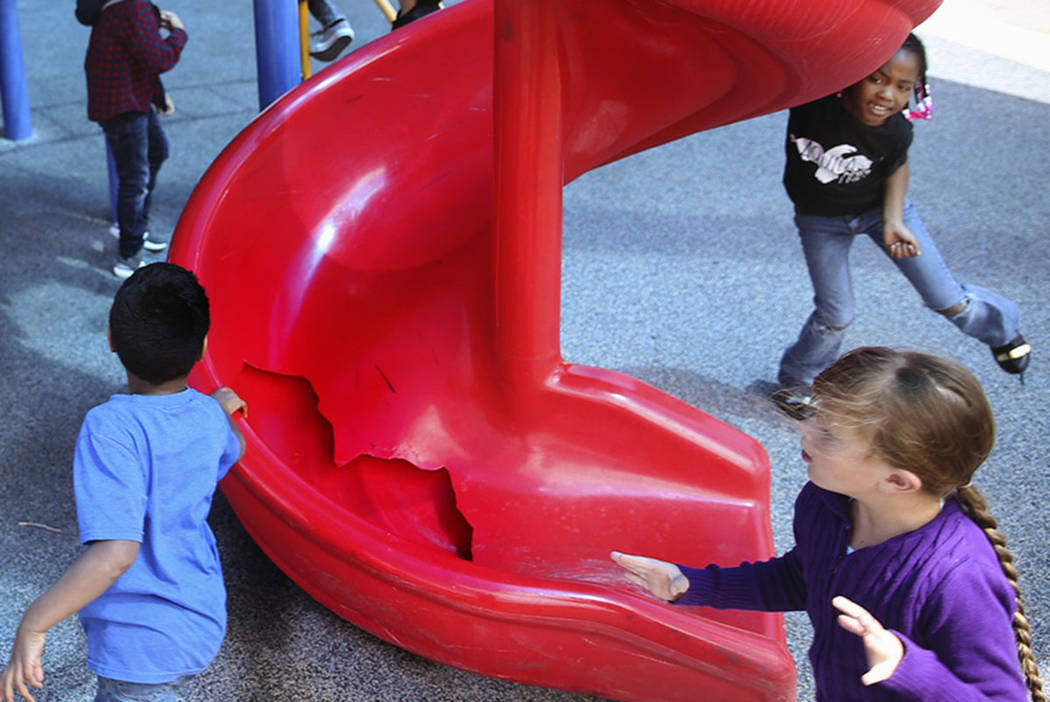 Students run around a broken slide in the playground at Helen Smith Elementary School in Las Ve ...