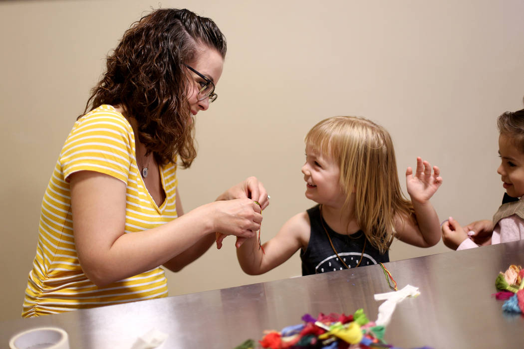 Whitney Jones ties a friendship on her daughter Penny Jones, 3, at the Mother's Day Morning of ...