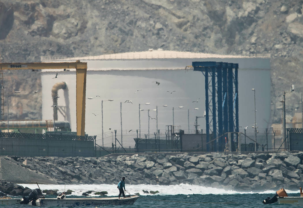 A fisherman prepares his boat near an oil storage tank in Fujairah, United Arab Emirates, Monda ...