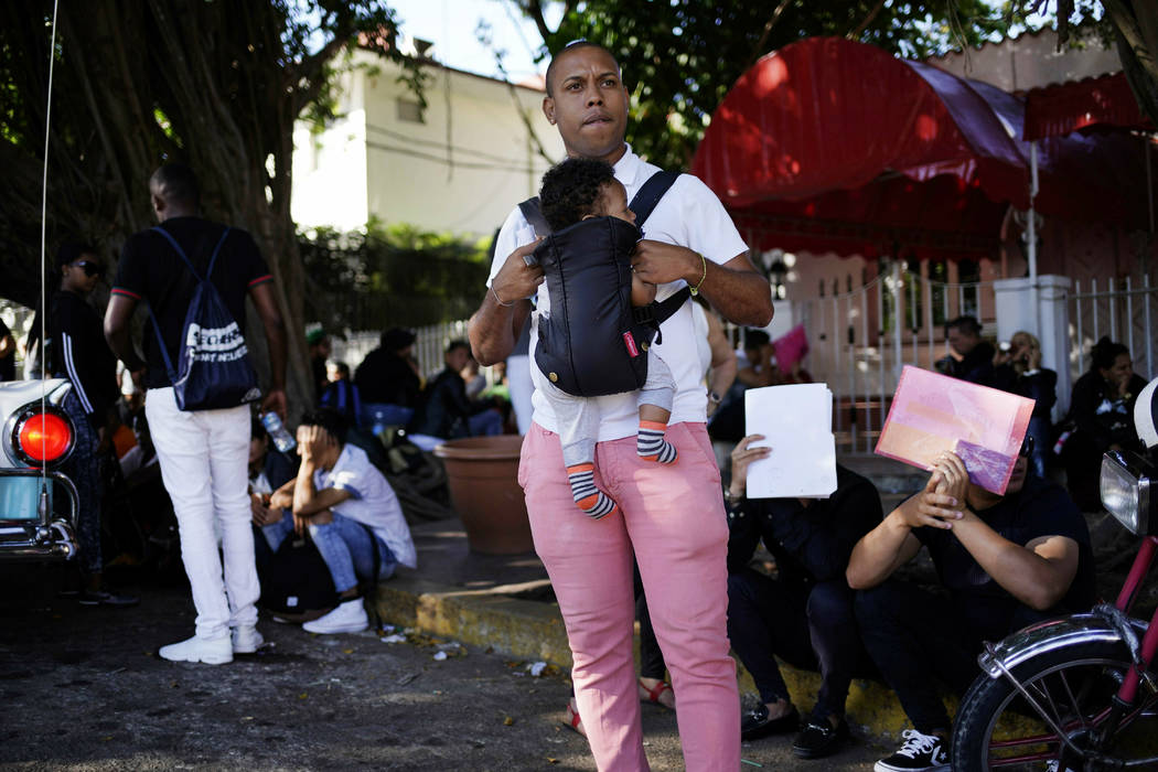 In this April 26, 2019, photo, a man holds his baby while he waits his turn to enter Nicaragua' ...