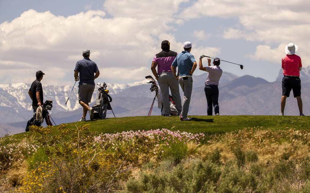 Golfers tee off with snow on Mt. Charleston as a background during a PGA US Open qualifying rou ...