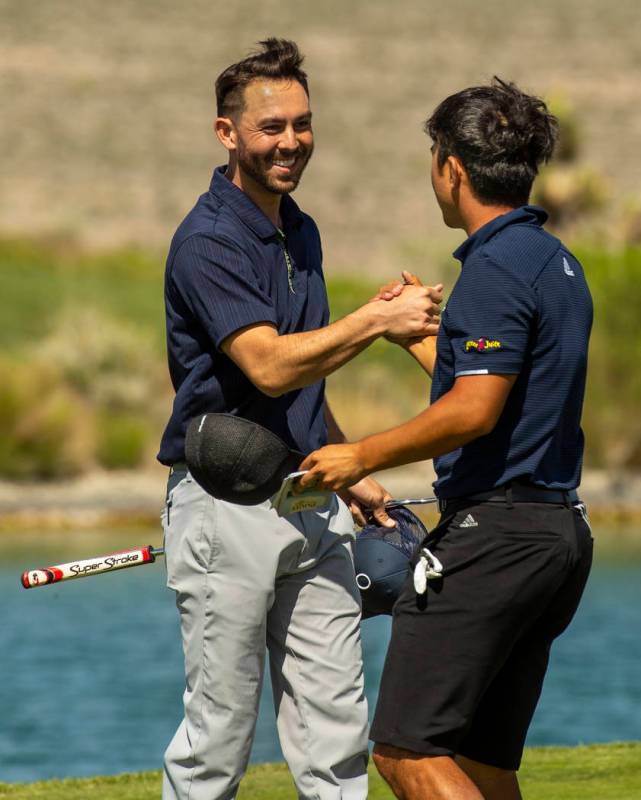 Golfers Brett Kanda and Alexander Kang celebrate their qualifying score on the 18th hole during ...