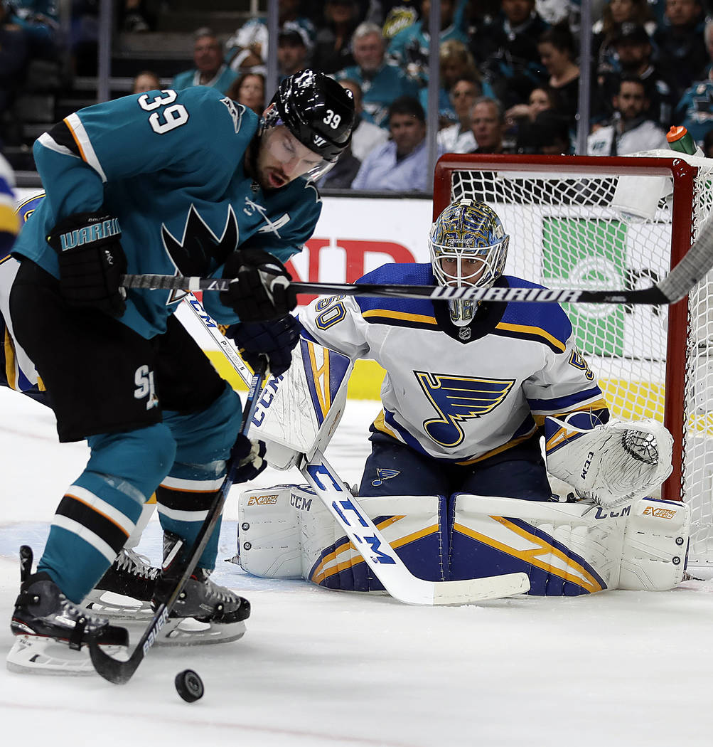 San Jose Sharks' Logan Couture, left, moves the puck against St. Louis Blues goalie Jordan Binn ...