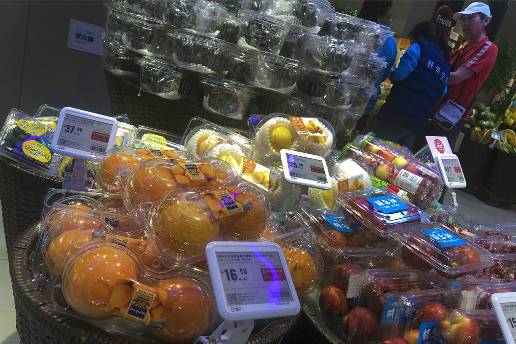 A man chats with workers near a fruit section selling oranges from the United States and fruits ...