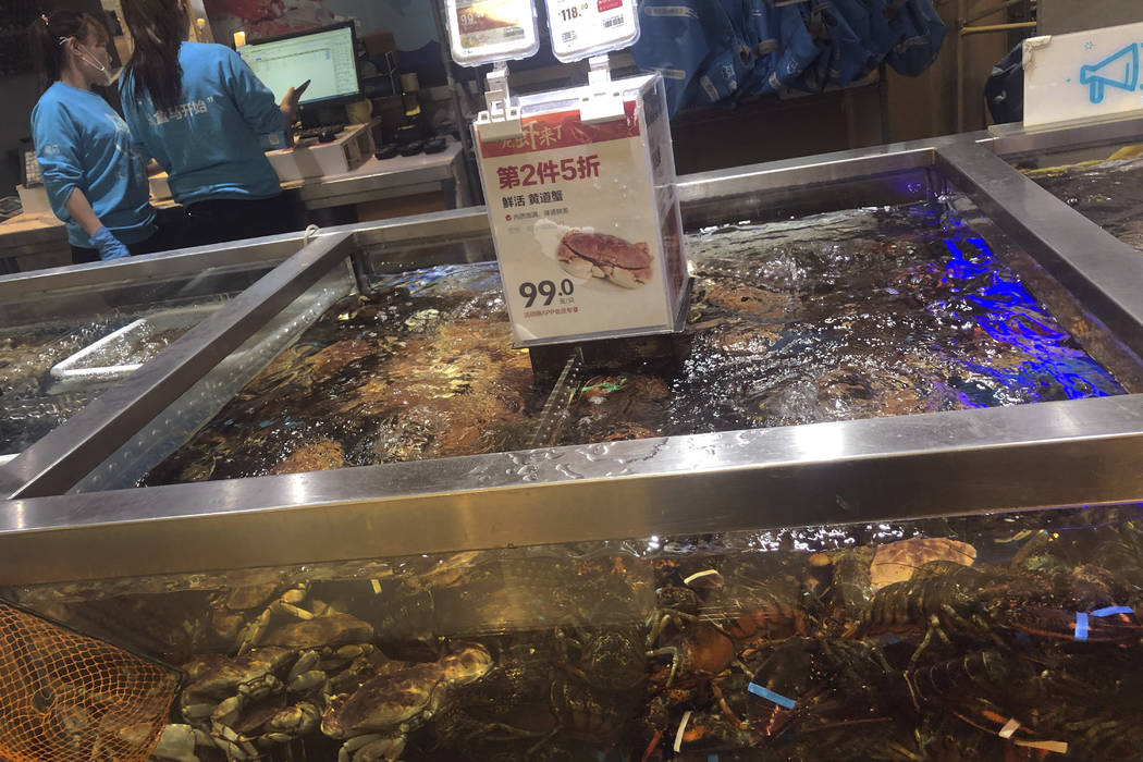 Workers check on seafood stock list near a water tank selling Boston lobsters and other seafood ...