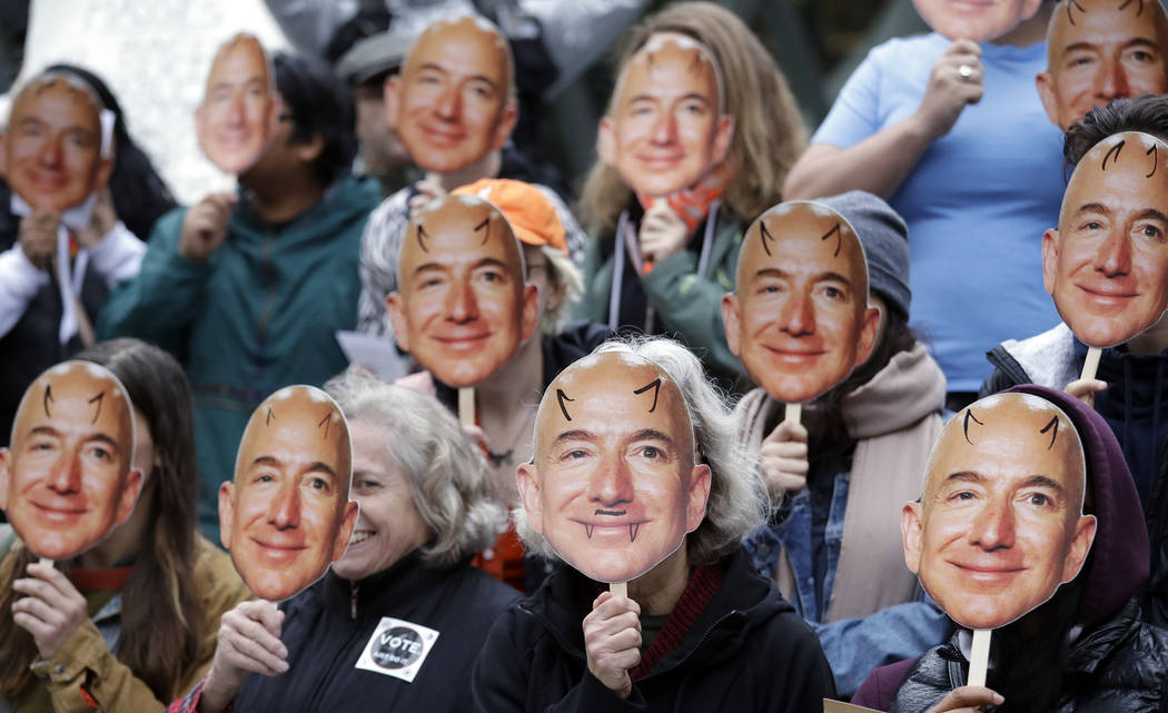 FILE - In this Oct. 31, 2018, file photo, demonstrators hold images of Amazon CEO Jeff Bezos ne ...