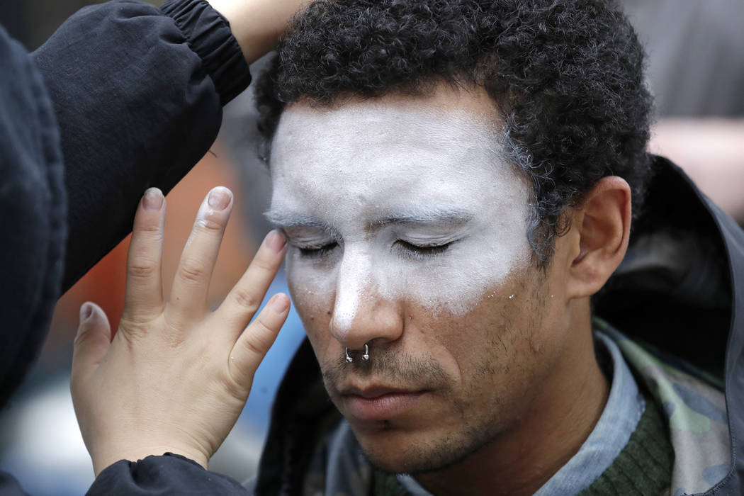 A man, who declined to be identified, has his face painted to represent efforts to defeat facia ...