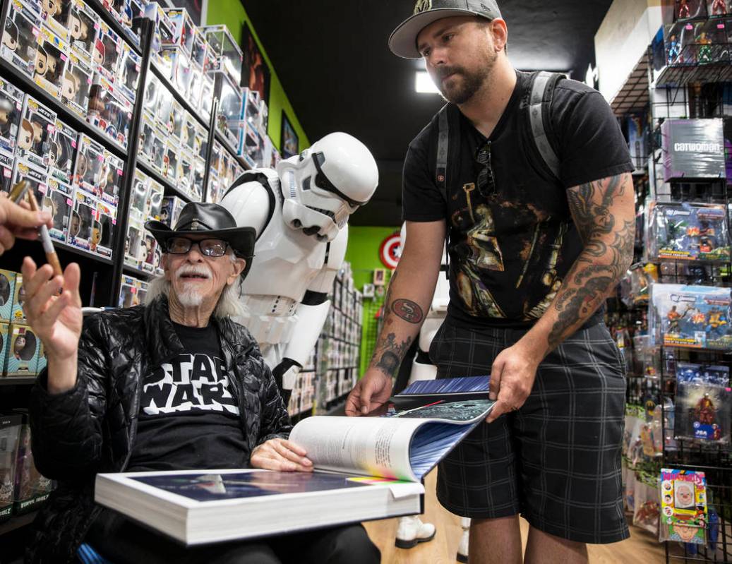 Colin Cantwell, left, concept artist and model builder for the original Star Wars movies, signs ...